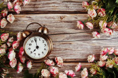 Pembe güller eşliğinde çalar saat Ahşap zemin üzerinde kenar çerçeve