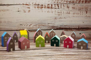 Ahşap arka planda düzenlenmiş renkli minyatür ev