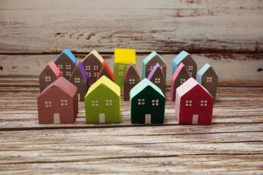 Ahşap arka planda düzenlenmiş renkli minyatür ev