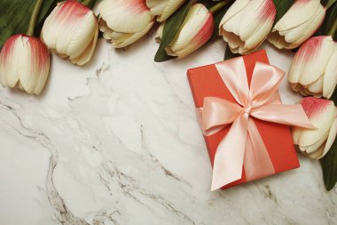 Pembe kurdeleli kırmızı hediye kutuları ve mermer arka planda lale çiçeği buketi
