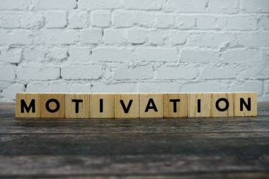 Ahşap arka planda motivasyon kelimesi alfabe harfleri
