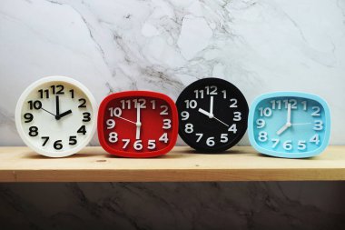 Ahşap raflarda ve mermer arka planda farklı ülkelerin zaman dilimine sahip saatler