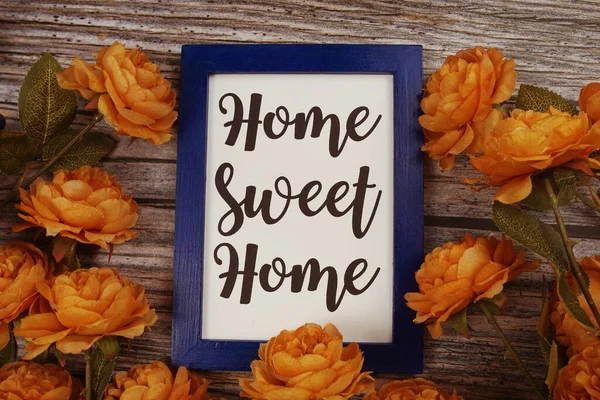 Home Sweet Home tipografi metni ve ahşap arka planda çiçek dekokasyonu