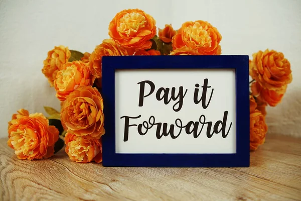 Pay it Forward text and flower bouquet on wooden table interior decoration