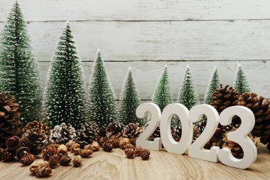 Noel ağacı ve ahşap arka planda çam kozalaklarıyla 2023 yılınız kutlu olsun.
