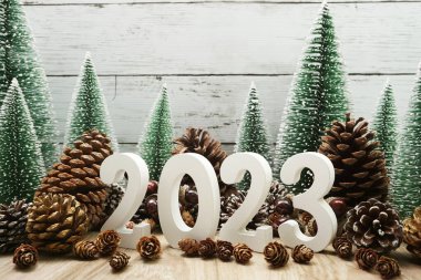 Noel ağacı ve ahşap arka planda çam kozalaklarıyla 2023 yılınız kutlu olsun.