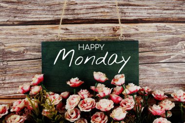 Ahşap arka planda pembe çiçek buketi olan mutlu pazartesi tipografi metinleri