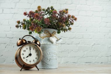 Alarm saati ve beyaz tuğla duvar arka planında yapay bitki dekoratifi