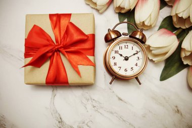 Alarmlı hediye kutuları ve mermer arka planda lale çiçeği buketi.