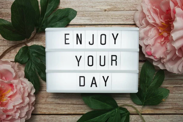 Enjoy Your Day text on lightbox on wooden background