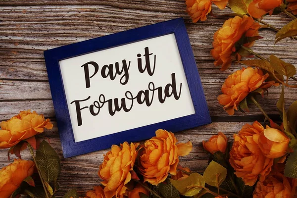 Pay it forward typography text with flower decoation on wooden background