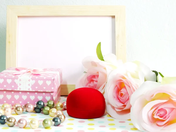 Leerer Fotoholzrahmen mit rosa Rosen und Geschenkbox auf süßer Blume — Stockfoto