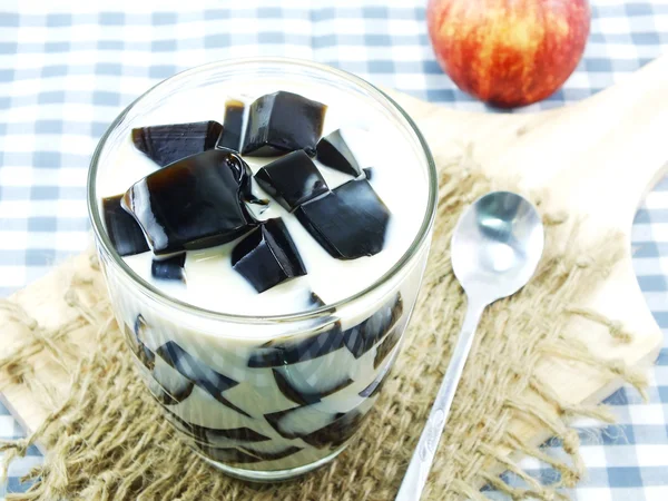 Thé au lait avec gelée noire en verre clair sur fond blanc — Photo