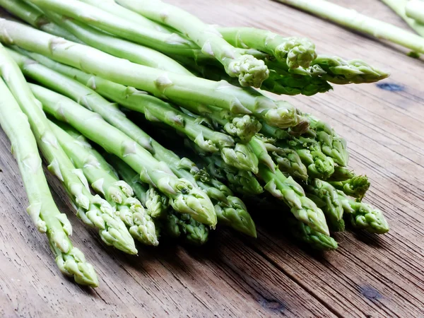 Espargos crus verdes em fundo de mesa de madeira — Fotografia de Stock