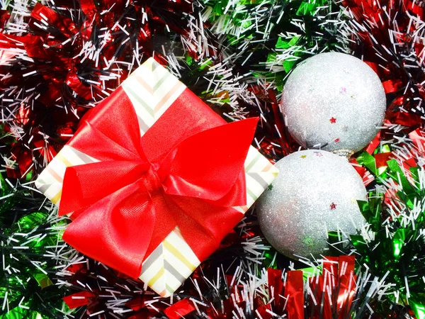 Caixa de presente presente com decorações de fita vermelha com fundo de Natal de ouropel vermelho e branco — Fotografia de Stock