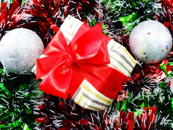 Caixa de presente presente com decorações de fita vermelha com fundo de Natal de ouropel vermelho e branco — Fotografia de Stock
