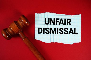 Haksız kovma metni yırtık kağıda yazılmış, ahşap yargı tokmağı kırmızı arkaplanda.