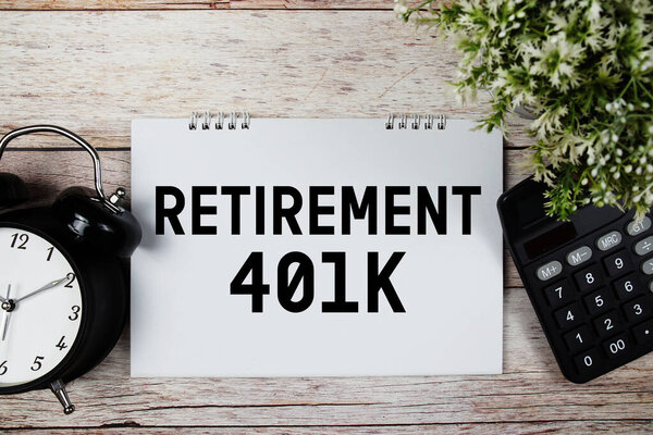 Текст пенсии 401K с будильником и калькулятором на деревянном фоне