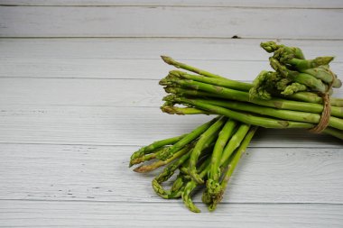 Ahşap arka planda bir sürü taze kuşkonmaz var.