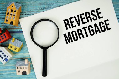 Üzerinde büyüteç ve ahşap arka planda ev modeli olan 