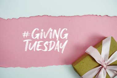 Giving Tuesday text with gift box present on pink background