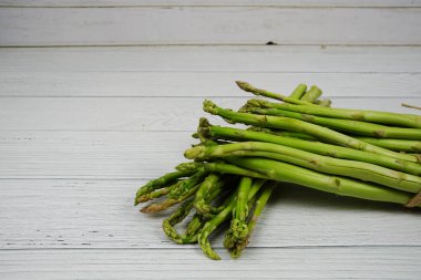 Ahşap arka planda bir sürü taze kuşkonmaz var.