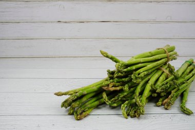 Ahşap arka planda bir sürü taze kuşkonmaz var.