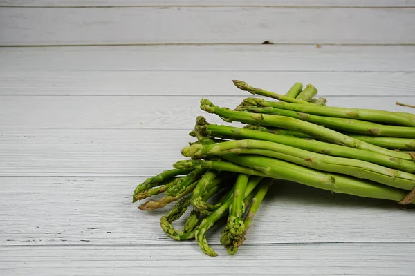 Ahşap arka planda bir sürü taze kuşkonmaz var.