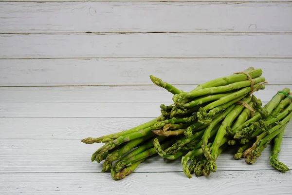 Ahşap arka planda bir sürü taze kuşkonmaz var.