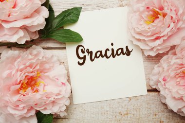 Ahşap zemin üzerinde çiçek buketi olan Gracias metni