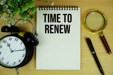 Alarm saati ve büyüteçle not defterine yazılan metni yenileme zamanı tahta zemin üzerinde yatıyordu