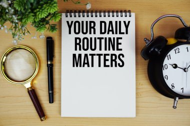 Not defterine alarm saati ve büyüteç düzlüğü ile tahta zemin üzerinde yazılı metni büyütmeye devam et.