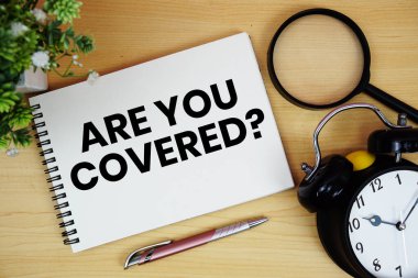 Korunuyor musun? Alarm saati ve büyüteçle birlikte not defterine yazılmış metin tahta zemin üzerinde yatıyordu