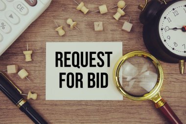 Not defterine kalem, alarm saati, büyüteç ve ahşap zemin üzerinde hesap makinesi ile yazılmış teklif metni talebi