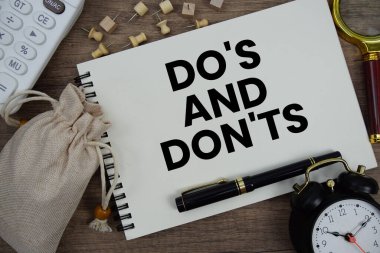 Not defterine kalem, alarm saati, büyüteç ve ahşap zemin üzerinde hesap makinesi ile 