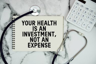 Sağlığınız bir yatırımdır, steteskop ve mermer arka planda hesap makinesi ile not defterine yazılmış bir harcama metni değil.