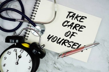 Not defterine steteskop ve mermer zemine alarm saati ile yazılmış kendine dikkat et.