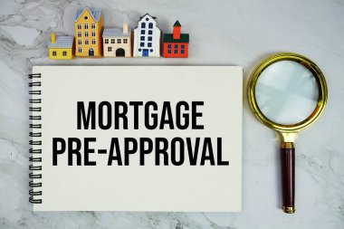 Ev modeli ve mermer arka planda büyüteçle birlikte not defterine yazılan ipotek öncesi metin