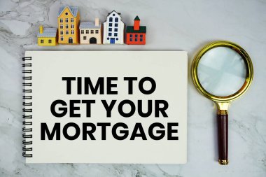 Ev modeli ve mermer arka planda büyüteçle birlikte ev kredisi metninizi not defterine yazdırma zamanı