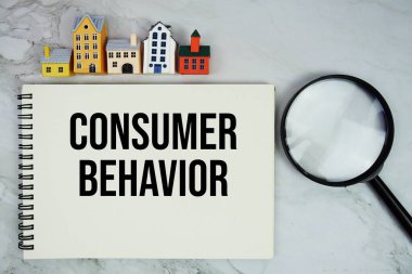 Ev modeli ve mermer zemin üzerindeki büyüteçle not defterine yazılan tüketici davranışı metni