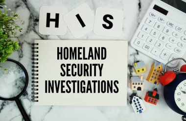 Ev modeli, hesap makinesi, büyüteç ve mermer zemin üzerindeki alarm saatiyle birlikte not defterine yazılmış İç Güvenlik Soruşturmaları metni