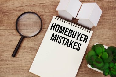 Ev alıcısı hataları metni ev modeli ve ahşap arka planda büyüteç içeren not defteri yazdı