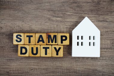 Ahşap arka planda ev modelli Pul Görev alfabesi harfleri