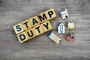 Ahşap arka planda ev modelli Pul Görev alfabesi harfleri