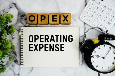 Mermer zemin üzerinde hesap makinesi ve alarm saati olan OPEX İşletim Masrafı metni