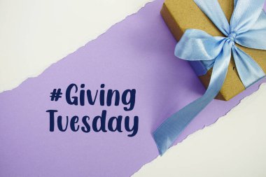 Giving Tuesday text with gift box present on purple background
