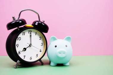 Pembe ve yeşil arka planda çalar saati olan Piggy Saving