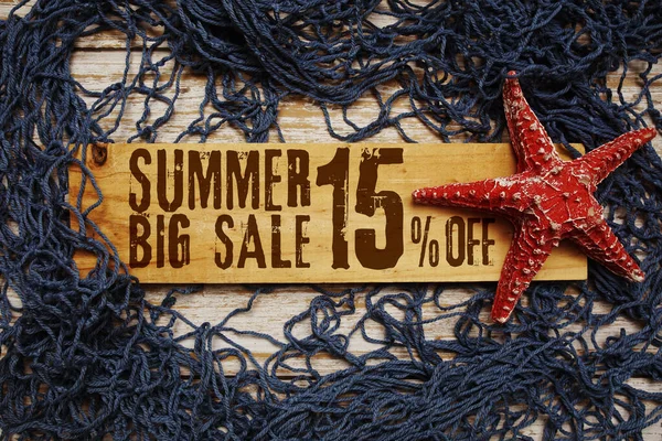 Yaz aylarında deniz yıldızı ve ahşap arka planda ağ ile süslenmiş ahşap tabelada% 15 indirim var.
