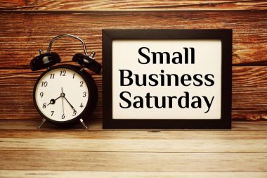 Ahşap zemin üzerinde alarm saati olan küçük işletme cumartesi metni