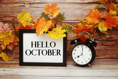 Merhaba Ekim metni alarm saati ve ahşap arka planda akçaağaç yaprağı süslemesi